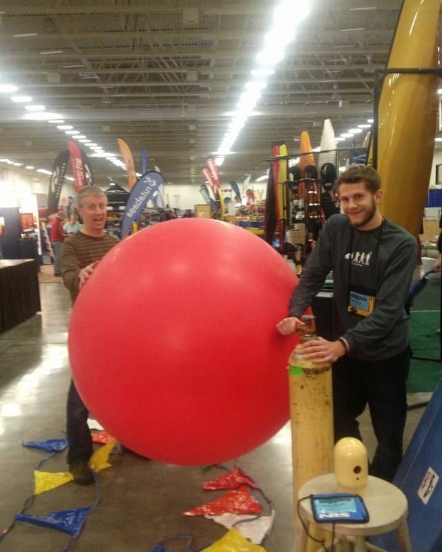 Brian and Bryan inflating a giant red balloon at a trade show