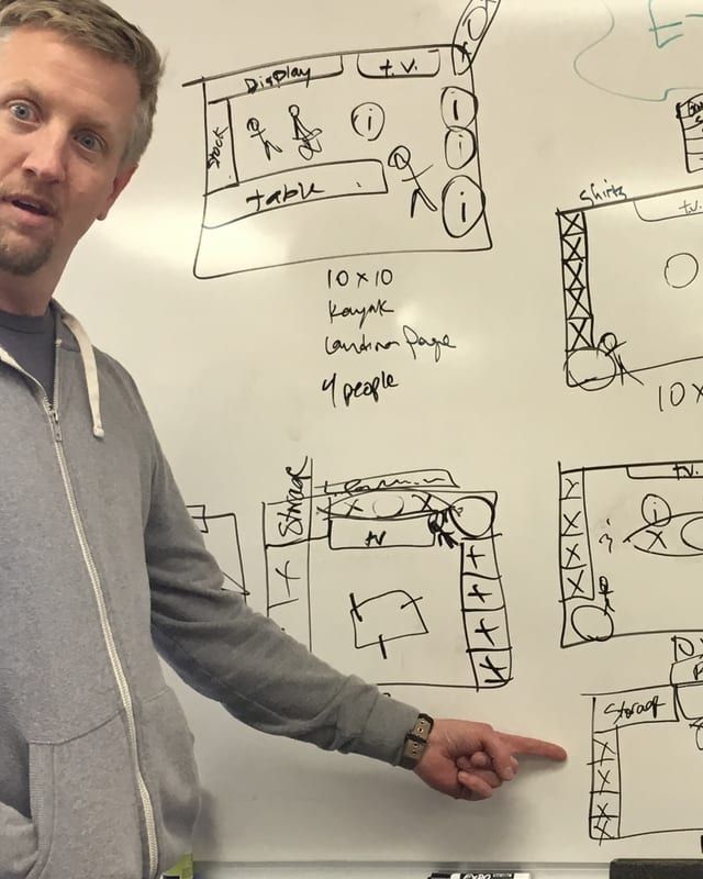 Brian sketching booth layouts on a whiteboard